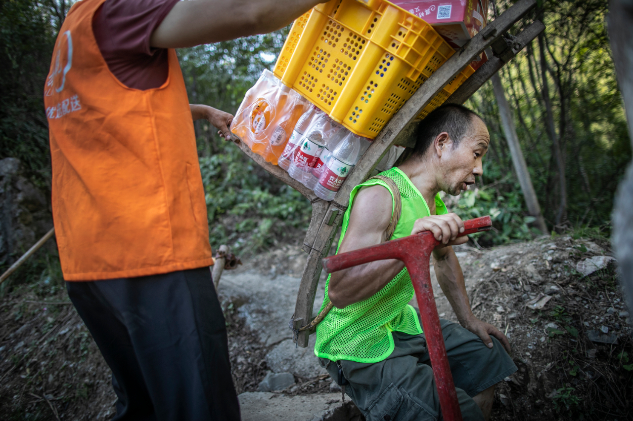 暴雨阻断进山路物流司机肩挑背扛送粮上山