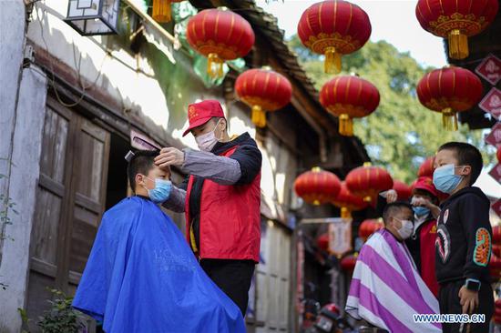 A volunteer barber cuts a boy's hair at a community in southwest China's Chongqing Municipality, Feb. 16, 2020. Since the outbreak of the novel coronavirus, most barbershops have been closed. A community in Beibei District of Chongqing organized a team of volunteer barbers to provide free haircuts for its residents. (Xinhua/Liu Chan)